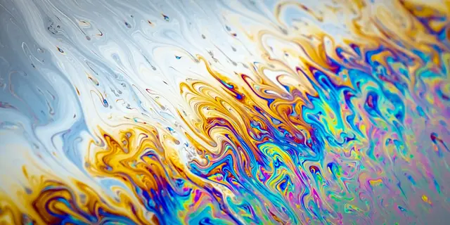 Pale blue, yellow, and violet fluid patterns flow across an abstract close-up.
